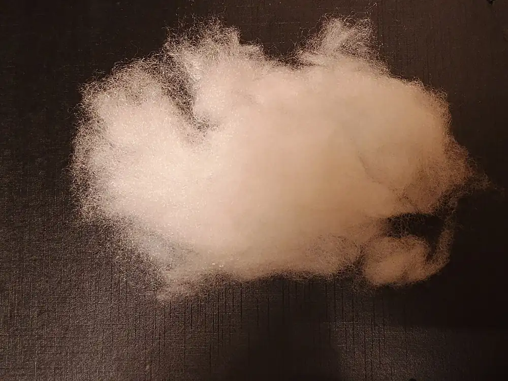 Loose white polyester fiberfill on a dark surface